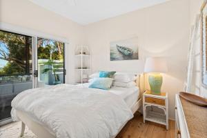 a white bedroom with a bed and a window at Kirby's Berrara Beach House in Berrara