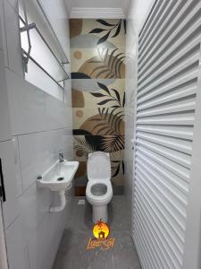 a bathroom with a toilet and a sink at Casa com piscina beira-mar in Mongaguá +4 photos