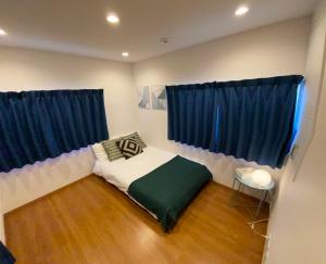 een slaapkamer met een bed en twee blauwe gordijnen bij Shin-Nakano House in Tokyo