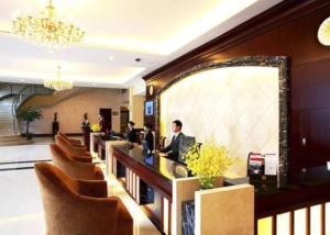um lobby de um hotel com um homem sentado em um balcão em Ramada Plaza Sino-Bay Shanghai em Fengxian