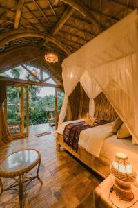 a bedroom with a canopy bed and a table at Arcada Bali Bamboo House in Sidemen +102 photos