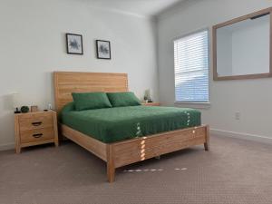 a bedroom with a bed with green sheets and a window at Sea La Vie - Large Family Friendly 4BR 10 Bed Pool and Bay Access in Orange Beach