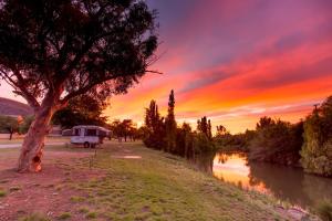 a camper parked under a tree next to a river at Paradise Tourist Park in Tamworth +68 photos