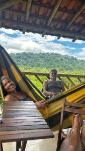 a man and a woman sitting in a hammock at Pousada Camping dos Ypês in Guapimirim
