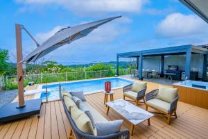 a pool deck with a couch and chairs and an umbrella at Villa MILA MOTOBU in Motobu
