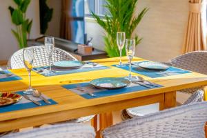 a wooden table with plates and wine glasses on it at Villa MILA MOTOBU in Motobu