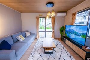a living room with a blue couch and a large tv at Villa MILA MOTOBU in Motobu +46 photos