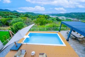 a swimming pool on a deck with an umbrella at Villa MILA MOTOBU in Motobu