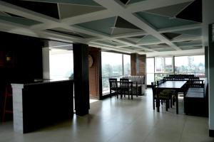 a dining room with tables and chairs and windows at Hotel Orchard Coorg in Virajpet
