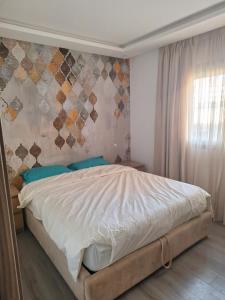 a bedroom with a bed and a wall with a window at Bel appartement familial résidence sécurisée in Casablanca