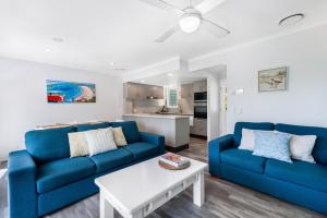 a living room with two blue couches and a table at Sails Lifestyle Resort in Peregian Beach