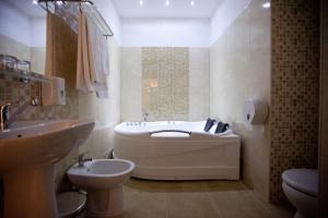a bathroom with a tub and a toilet and a sink at Hotel Poarta Transilvaniei in Bistriţa