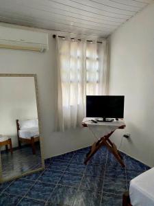 a room with a mirror and a table with a television at La Mar Paraty Hospedaria 02 in Paraty