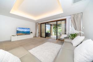 a living room with a white couch and a tv at Luxury 2 Bedrooms Villa Bangtao in Ban Pa Khlok
