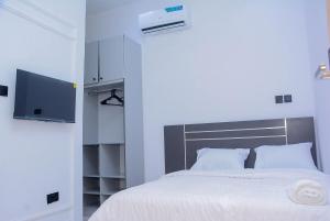 a bedroom with a bed with white sheets and a television at Stylish Haven, Luxe & Cozy in Mama