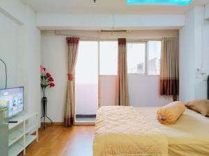 Un dormitorio con una cama y un televisor y una ventana. en The Royale Sentra Tower Kuning Powered by Cocotel, en Yakarta 45 fotos más