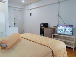 Un dormitorio con una cama y un televisor. en The Royale Sentra Tower Kuning Powered by Cocotel, en Yakarta