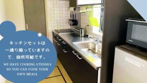 a small kitchen with a sink and a microwave at ゲストハウスガーデンズmihama in Wada
