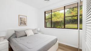 a white bedroom with a bed and a window at Government House, 35 Government Road - pet friendly , water views in Nelson Bay