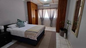 a small bedroom with a bed and a window at Pangolin Overnight Self-catering Accommodation cc in Windhoek