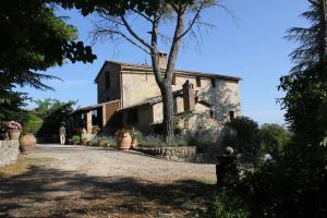 an old stone house with a tree in front of it at Torre Di Sant'Ansano in Corsano