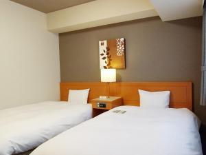 Postel nebo postele na pokoji v ubytování Hotel Route-Inn Niigata Kencho-minami