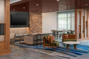 a lobby with chairs and tables and a flat screen tv at Fairfield Inn & Suites by Marriott New Orleans Metairie in Metairie