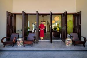 a woman in a red dress standing in a doorway at Hoianoi Villa_A Little Hoi An_Entire villa in Hoi An +59 photos