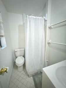 a bathroom with a toilet and a white shower curtain at Cozy House St Johns Bluff in Jacksonville