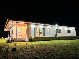a large white house with lights on it at night at Japanese-inspired minimalistic house in Ban Bang Mak