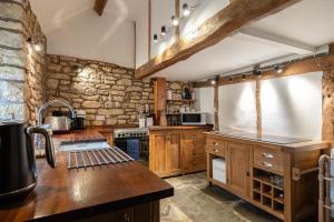 a kitchen with wooden cabinets and a stone wall at Orchard Cottage - Beautiful Home near Broadway! in Weston Subedge