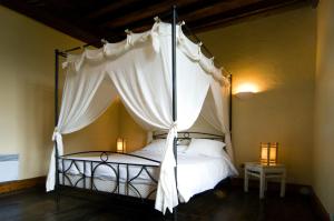 サン・テティエンヌ・ド・バイゴリにあるChambres d'Hôtes Jauregiaのベッドルーム(白いカーテン付きの天蓋付きベッド1台付)