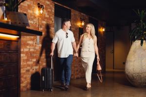 a man and woman walking down a hallway with a suitcase at Hotel Indigo Brisbane City Centre by IHG in Brisbane