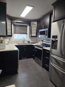 a kitchen with black cabinets and stainless steel appliances at Full House - Main Floor in Regina +13 photos
