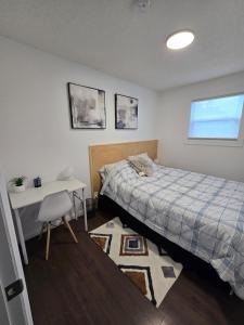 a bedroom with a bed and a table and a desk at Full House - Main Floor in Regina