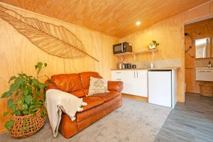 汉密尔顿Boutique Country Retreat -Outdoor bath的一间带棕色真皮沙发的客厅和一间厨房