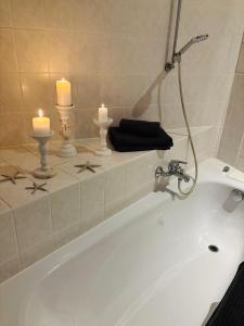 a white bath tub with two candles and two candles at moderne Ferienwohnung am Stadtwald von Plauen in Plauen +6 photos