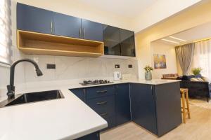 a kitchen with blue cabinets and a living room at Serenity Haven Najeera in Kira