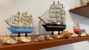 a shelf with three model ships and shells on it at Tierra Bella-Exclusive Beachfront Villa at Elyu in Bauang