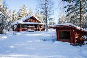 une cabane en rondins dans la neige avec des arbres enneigés dans l'établissement Loma Rinteelä, à Suonenvaara