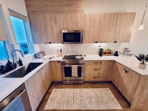 a kitchen with wooden cabinets and a stainless steel oven at Luxe & Bright Gem - Prime Location, Roof Deck, View in Seattle +37 photos