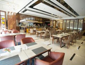 uma sala de jantar com mesas e cadeiras num restaurante em Parklane Hotel Changan em Dongguan