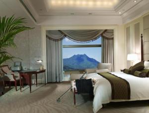 een slaapkamer met een bed, een bureau en een raam bij Parklane Hotel Changan in Dongguan