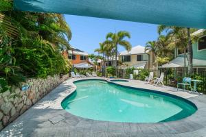 a swimming pool in a yard with chairs and trees at Sails Lifestyle Resort in Peregian Beach