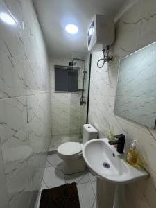 a white bathroom with a toilet and a sink at Elysia by Joja in Lagos