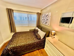a small bedroom with a bed and a window at Kingsleigh Apartments Sydney in Sydney +65 photos