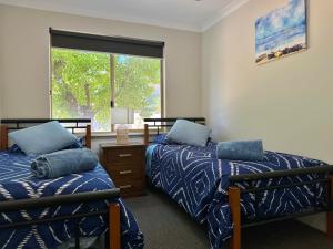 a bedroom with two beds and a window at Pelican Shore Villa 19 - Kalbarri WA in Kalbarri