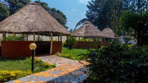 two huts with thatched roofs in a garden at Malava-K-Resort in Kakamega