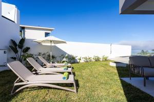 due sedie a sdraio e un ombrellone su un prato di Gorvorana Norte - private pool, BBQ, 8pax a Realejo Bajo