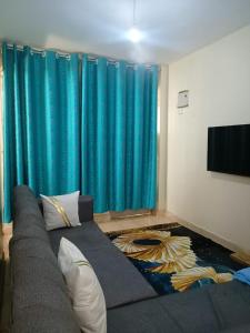 a couch in a living room with blue curtains at Bnb kamakis in Ruiru